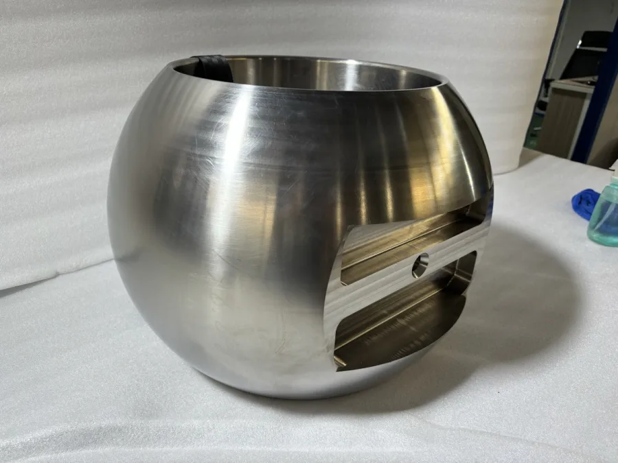 A machined hollow spherical component with an opening and detailed inner surfaces