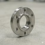 Titanium slip-on flange seen from above at an angle, showing the serrated face finish and the open bore