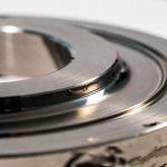 Close-up of the machined raised face of a titanium flange, showing the concentric finish grooves