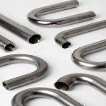 Multiple U-shaped and straight titanium heat exchanger coil sections displayed, custom fabricated titanium tubing