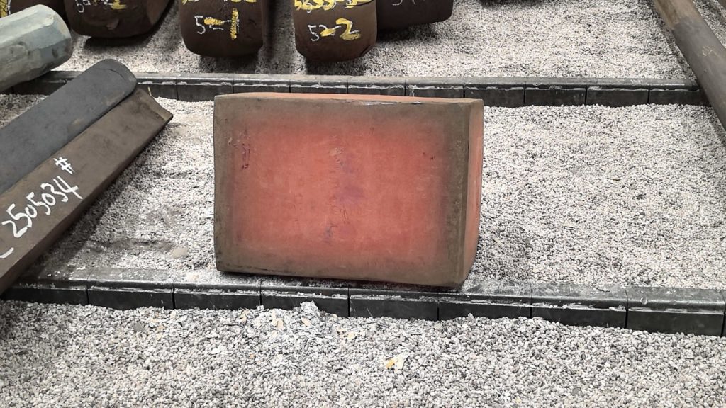 Forged Grade 5 titanium slab with surface oxidation tint beside marked billets