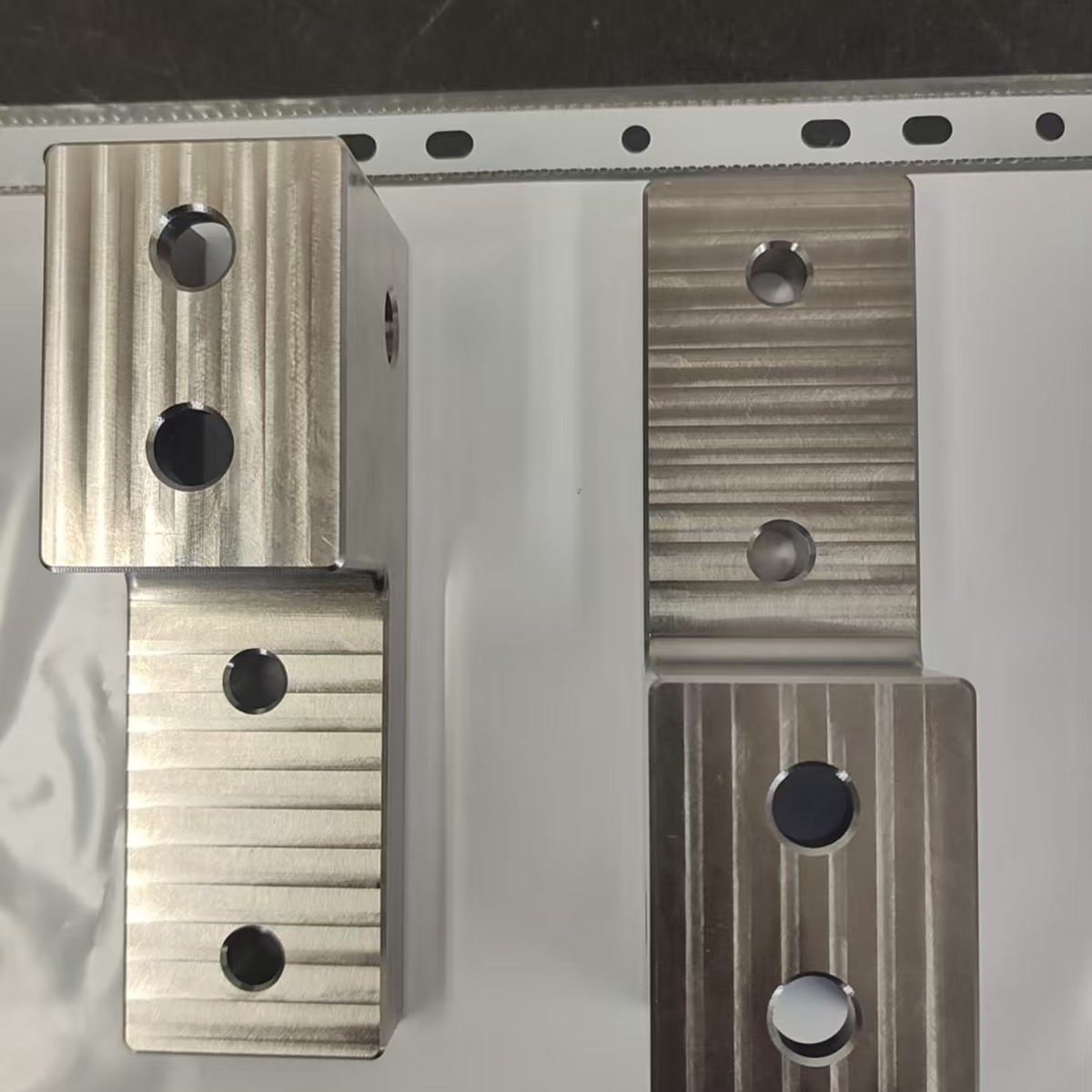 Finished titanium brackets from an anonymized German automotive machining project