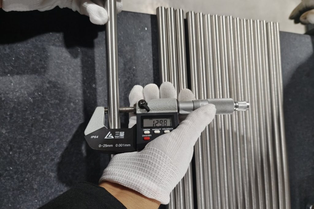 Digital micrometer reading titanium bar diameter on a granite surface plate