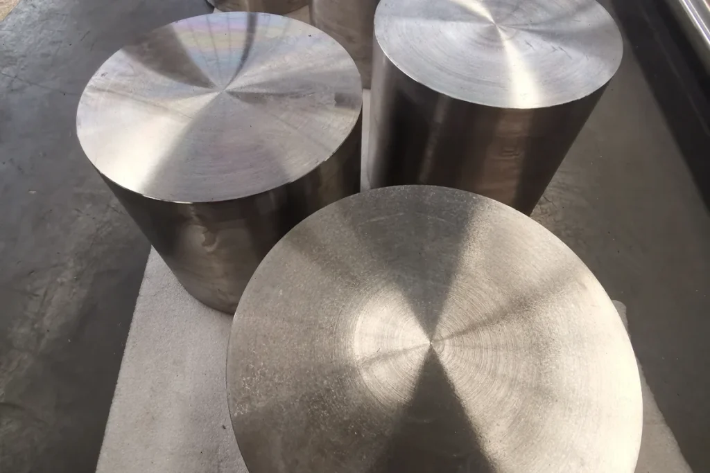 Titanium forged disc alongside round bar stock, showing shape families ordered against a drawing
