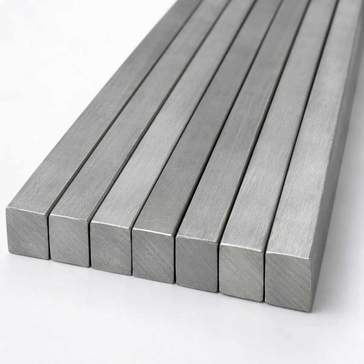 Titanium square bar in a parallel stack with the solid square cross sections facing the camera, illustrative studio image of the product form